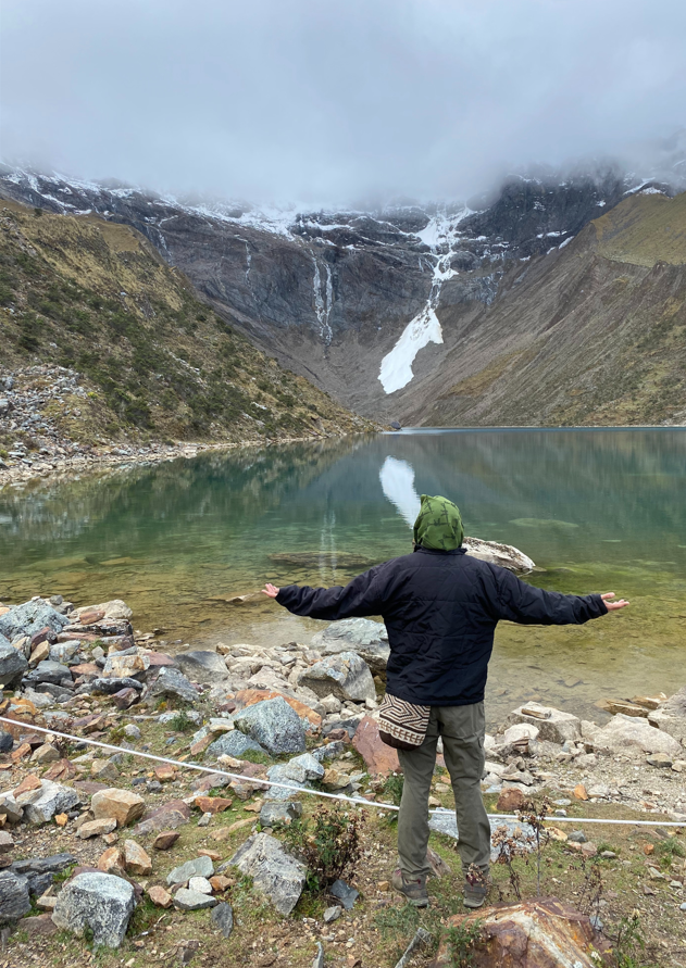 Momento de meditación y espiritualidad natural frente a una laguna rodeada de picos nevados y aire puro.