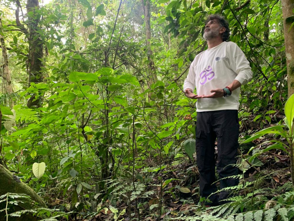 Guía practicando baño de bosque en un sendero rodeado de vegetación tropical, conectando con la naturaleza a través de la respiración y la contemplación